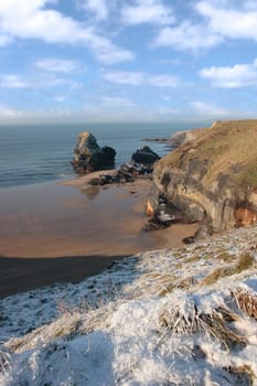 snow covered view of beach cliffs and the virgin rock in ballybunion county kerry ireland