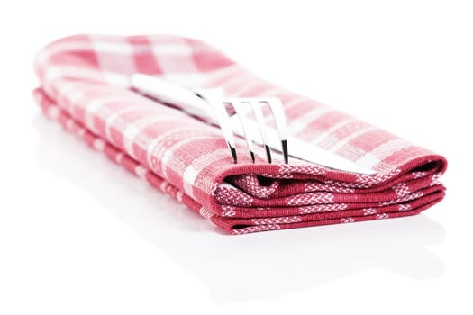 Cutlery on a red and white checkered tea towel on a white background