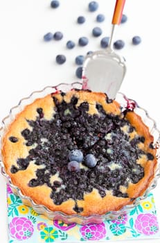 Closeup of delicious blueberry pie in glass dish with serving utensil