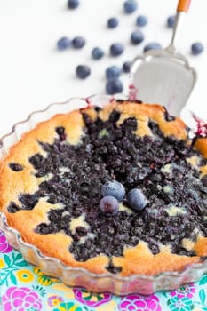 Closeup of delicious blueberry pie in glass dish with serving utensil