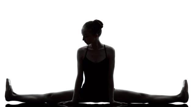 one caucasian young woman ballerina ballet dancer stretching warming up in silhouette studio on white background