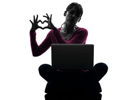 one caucasian woman heart gesture computing laptop computer  in silhouette studio isolated on white background