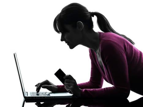 one caucasian woman holding credit card  computing laptop computer  in silhouette studio isolated on white background