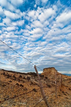 Old worn out fence in a desolate desert under a dramatic blue sky