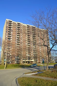 A 19 story high rise condominium building in the fall under blue sunny  sky.