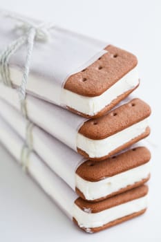 Closeup of stack of vanilla ice cream biscuits wrapped in white paper with string and bow on light background