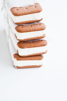 Closeup of stack of vanilla ice cream biscuits wrapped in white paper with string and bow on light background