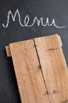 Closeup of wooden board and word menu written in chalk on dark background