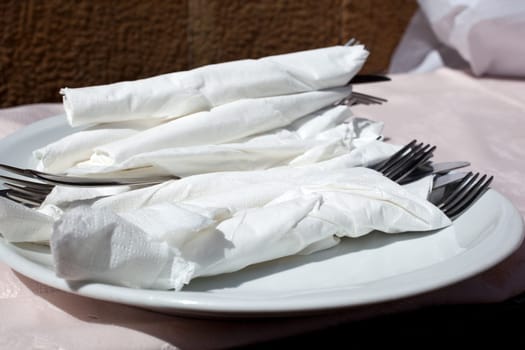 Plate with forks and knives wrapped in napkins