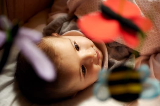 Children playing at home, happy cute little girl smiling and playing with toys and puppets in bed
