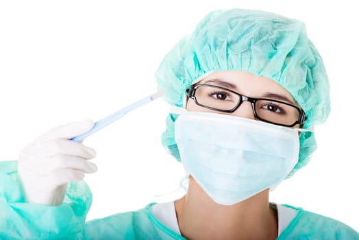 Portrait of woman doctor or nurse with surgical mask and cap holding scalpel