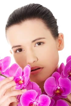 Portrait of beautiful young woman with health skin and with orchid flower. Spa concept.