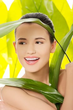 Portrait of young beautiful woman with green leafs in background