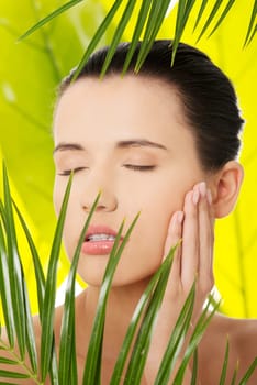 Portrait of young beautiful woman with green leafs in background