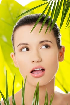 Portrait of young beautiful woman with green leafs in background