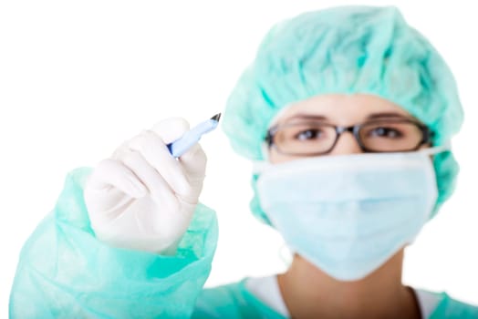Portrait of woman doctor or nurse with surgical mask and cap holding scalpel