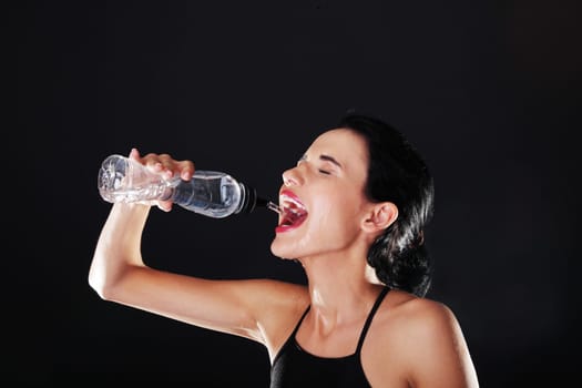 Sport woman cooling herself with water, over black background