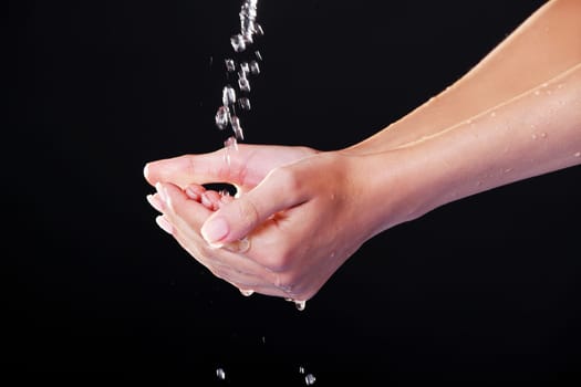 Water falling on female hands, over black background