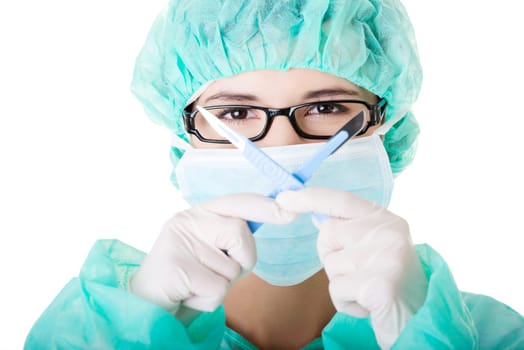 Portrait of woman doctor or nurse with surgical mask and cap holding scalpel