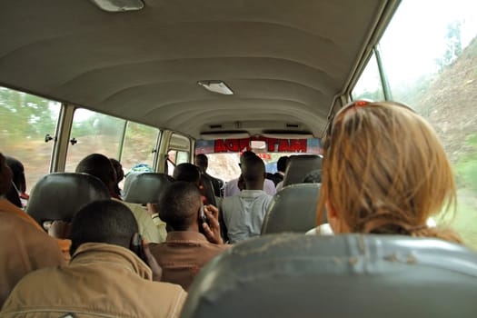 Rwandans travelling on a public bus talking on cell phones. Pictures also shows difference in hair growth between Africans and a Caucasian woman.