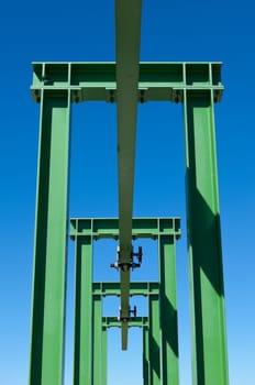 Detail of a small gantry crane painted green against the blue sky
