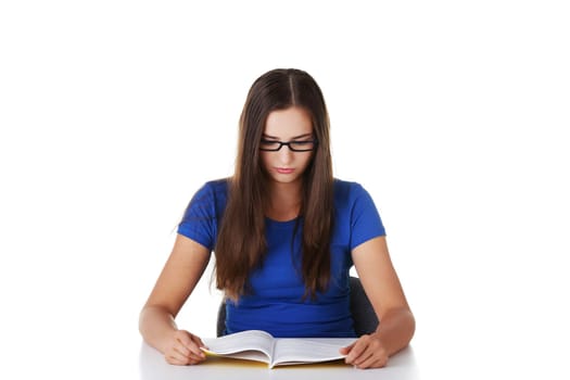 Teen girl learning at the desk, isolated on white
