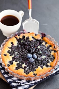 Blueberry pie in glass dish and server and coffee in white cup