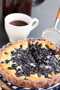 Closeup of blueberry pie in glass dish and server and coffee in white cup