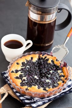 Blueberry pie in glass dish and server and coffee plunger and cup