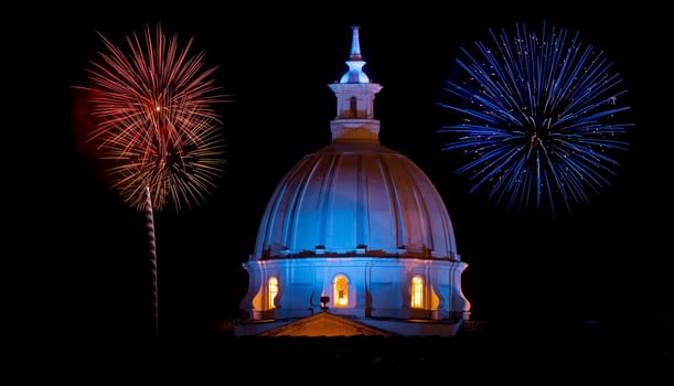 The dome of the cathedrel in Popayan, Colombia at night with blue and red fireworks going off