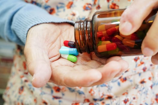 Asian elderly woman holding pill drug in hand, strong healthy medical concept. 