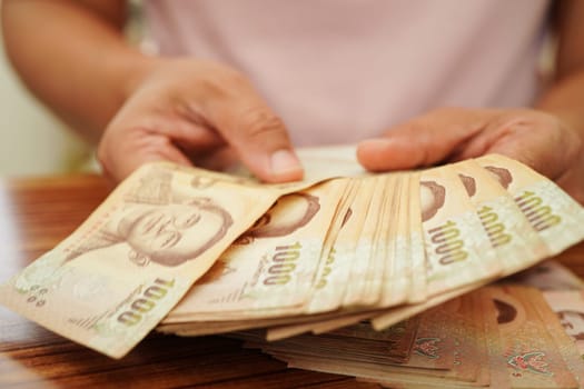 Asian woman counting Thai baht banknote money and holding in hand, investment economy, accounting business and banking.