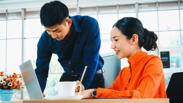 Two business people talk project strategy at office meeting room. Businessman discuss project planning with colleague at modern workplace while having conversation and advice on financial report. Jivy