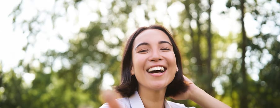 Genuine people. Portrait of asian woman laughing and smiling, walking in park, feeling joy and positivity.