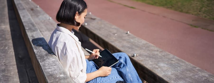 Happy asian girl, artist scratching smth, drawing on digital tablet with graphic pen.