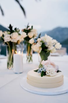 Wedding cake decorated with flowers stands on a plate on the table. High quality photo