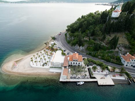 Cozy hotel on a green cape with a beach and a pier. Lepetane, Montenegro. Drone. High quality photo