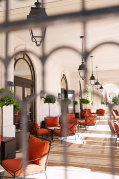 View through the wrought-iron lattice onto the hotel terrace with soft chairs and tables. High quality photo