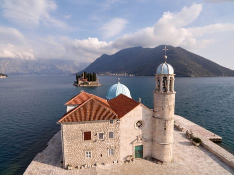 Ancient stone church of Our Lady on the rocks on the island of Gospa od Skrpjela Montenegro. Drone. High quality photo