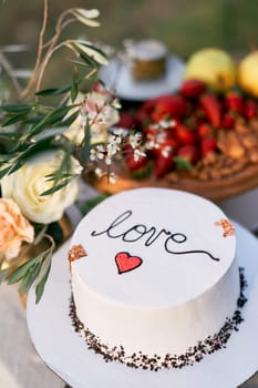 Wedding cake is on the table next to the bouquet of flowers. Caption: Love. High quality photo
