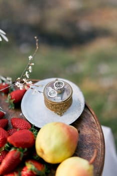 Wedding rings lie on a casket on a platter of fruit on the table. High quality photo