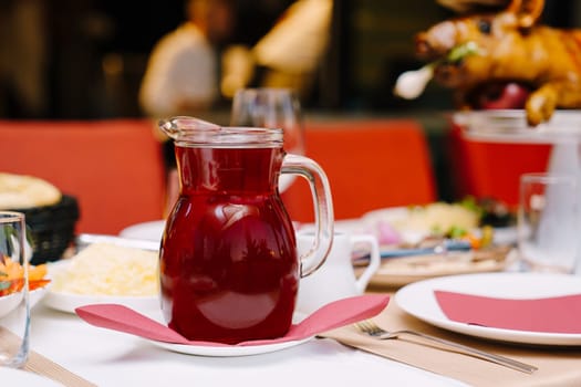 Decanter of berry juice stands on a laid table in a restaurant. High quality photo