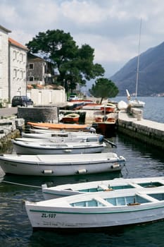 Row of white fishing boats stands on the pier of Perast. Montenegro. High quality photo