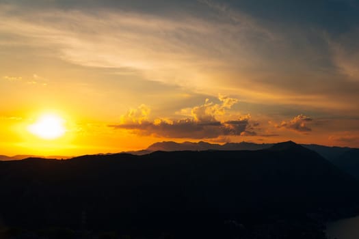 Orange sunset in the sky over a mountain range. High quality photo