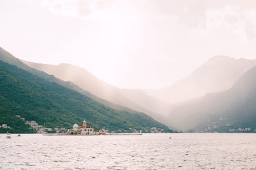 Island of Gospa od Skrpjela in the Bay of Kotor against the backdrop of mountains in the sunlight. Montenegro. High quality photo