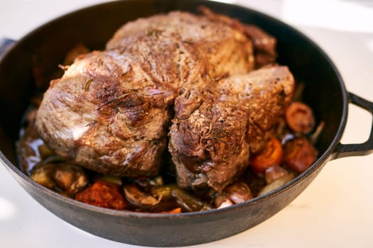 Frying pan with juicy roast beef and stewed vegetables on the table. High quality photo