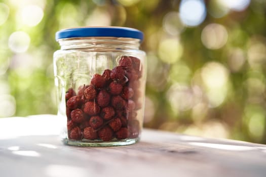 Glass jar with dried rose hips stands on a table on the balcony. High quality photo