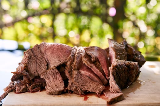 Slices of juicy roast beef lie on a cutting board on a glass table. High quality photo