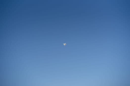 White drone soars in the blue sky. Bottom view. High quality photo
