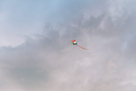 Multicolored kite soars in the cloudy sky. High quality photo
